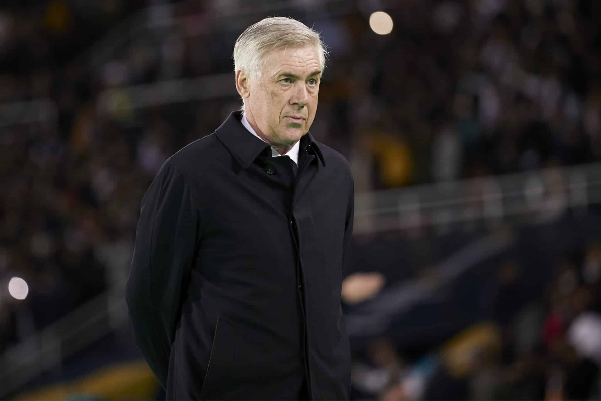 Técnico Carlo Ancelotti olha para a frente com os braços cruzados atrás das costas