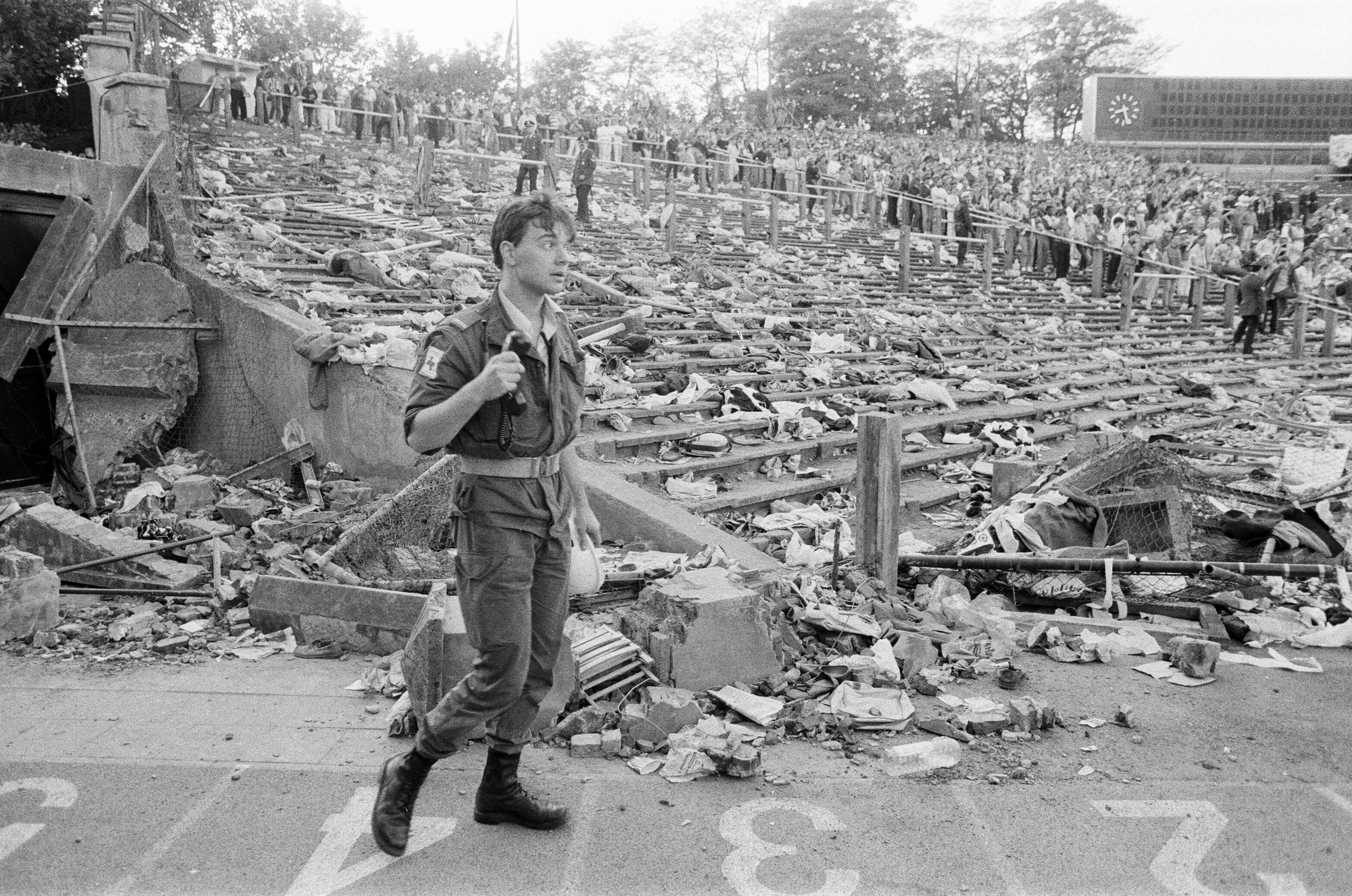 Policial em frente a destroços de muro que desabou e arquibancada vazia no Estádio de Heysel