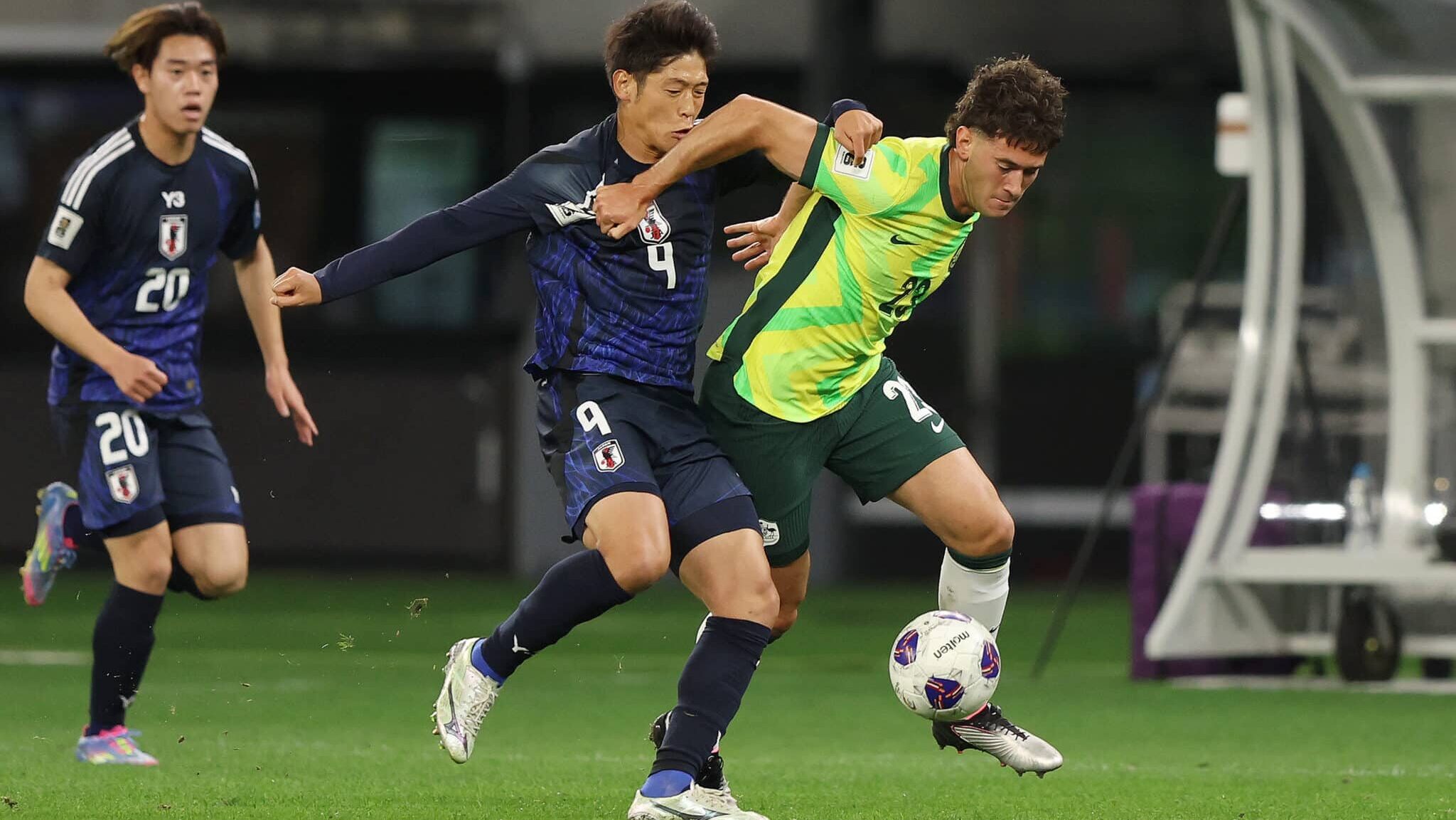 Jogador do Japão tenta tirar a bola de jogador da Austrália