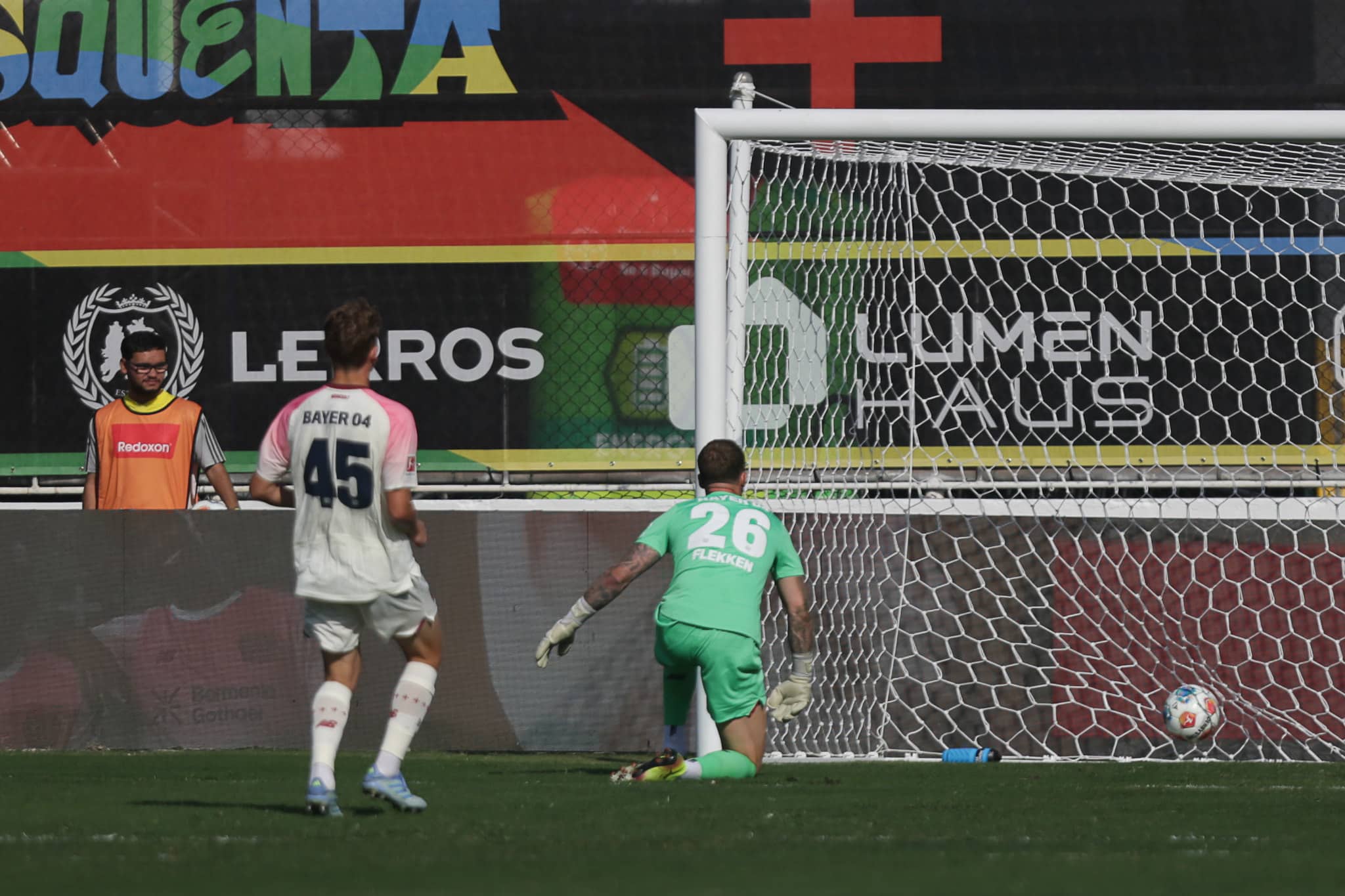 Zagueiro e goleiro do Bayer Leverkusen olham a bola no fundo da rede